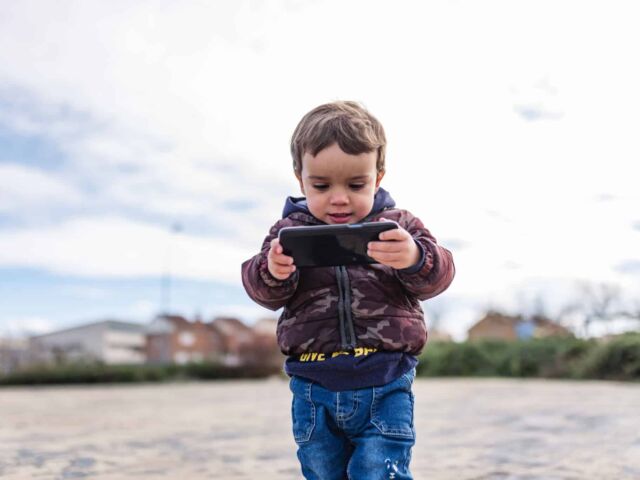 Children surfing the internet outdoors on a iPhone